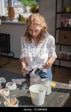 Produktionsprozess der Keramik. Anwendung der Glasurbürste auf Keramikgeschirr. Stockfoto