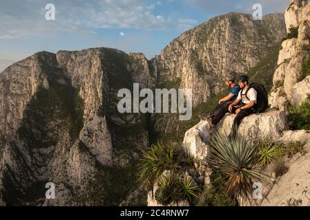 Zwei Freunde sitzen auf einem Felsen in einem Höhepunkt In La Huasteca Stockfoto