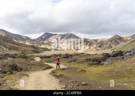 Männlicher Wanderer, der den leeren felsigen Weg in Island hinunter geht Stockfoto