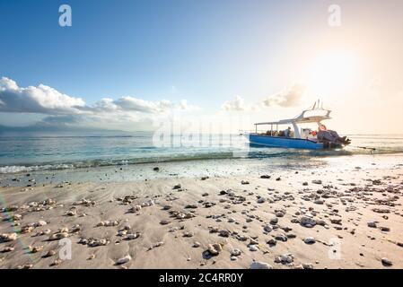 Ein Motorboot, das zum Tauchen in Nusa Penida, Bali, Indonesien, an einem Kiesstrand bei Sonnenaufgang vor Anker liegt. Tauchen Stockfoto