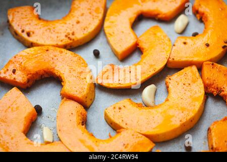 Helle Kürbisscheiben, die zum Backen im Ofen vorbereitet werden. Weichfokus. Stockfoto