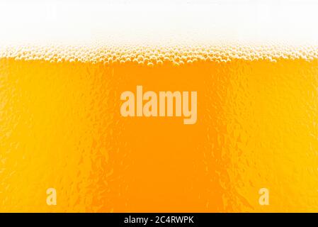 Makroaufnahme von Bier in einem Glas mit sichtbarem Schaum und Wassertropfen. Stockfoto