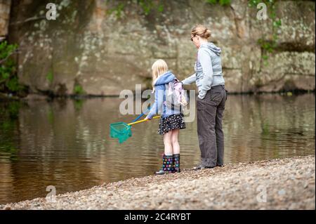 Eine Mutter und Tochter mit Fischernetzen am Flussufer. Stockfoto