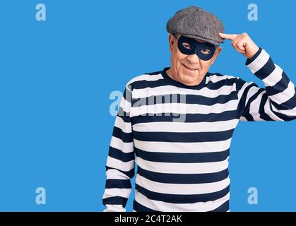 Senior stattlichen Mann trägt Einbrecher Maske und T-Shirt lächelnd zeigt auf den Kopf mit einem Finger, große Idee oder Gedanken, gute Erinnerung Stockfoto
