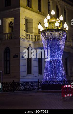 Winter Nacht Stadt mit blauen und gelben Lichtern und Brunnen im Park Stockfoto