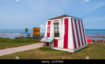 Rettungsschwimmerstation in der Nähe eines belebten Strandes. Promenade und Warnschilder. Blauer Himmel und ruhiges Wasser. Stanhope Beach, Prince Edward Island National Park, Kanada Stockfoto