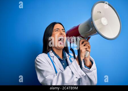 Hispanische Ärztin mit medizinischem weißen Mantel schreiend wütend auf Protest durch Megaphon. Schreien aufgeregt auf Ludspeaker reden und schreiende Nachrichten Stockfoto