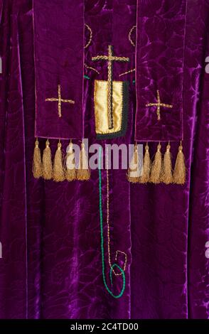 Liturgische Gewänder des Priesters. Violetter Samt mit goldenen Kreuzen und Quasten. Nahaufnahme zeigt Symbole des christlichen Gottesdienstes an Festtagen. Stockfoto