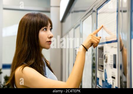 Junge Frau kauft Fahrkarten für öffentliche Verkehrsmittel Stockfoto