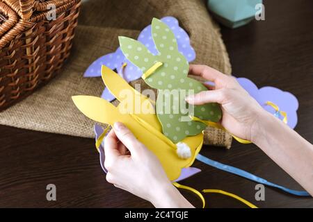 Osterdekoration, mehrfarbige handgefertigte Osterkaninchen in Frauenhand. Stockfoto