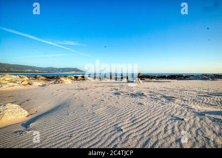 Sand vor dem Wasser unter dem blauen Himmel Stockfoto