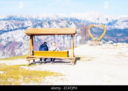 Junge Touristen sitzen auf einer Bank und schauen sich die wunderschöne Landschaft von Vogel, Slowenien an. Stockfoto