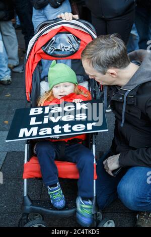 Seattle, USA. November 2015. Ein kleines Mädchen im Kinderwagen hält ein Black Lives Matter Zeichen begleitet von ihrem Vater bei der BLM-Kundgebung. Stockfoto