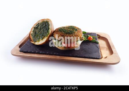 Köstlicher veganer Burger mit geschnittenen Tomaten und Rote Bete Blättern Ein Holzbrett Stockfoto