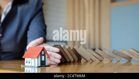 Schützen Sie das Haus vor dem Sturz über die Holzblöcke, Versicherung und Risiko-Konzept. Stockfoto