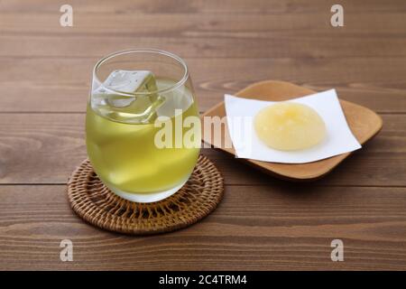 Glas kalten grünen Tee trinken mit Reiskuchen isoliert auf Holztisch Stockfoto