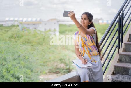 College Mädchen außerhalb des Hauses beobachten Online-Klasse aufgrund langsamer Internetverbindung - Konzept des Netzwerkproblems an entfernten Orten und Problem der virtuellen Stockfoto