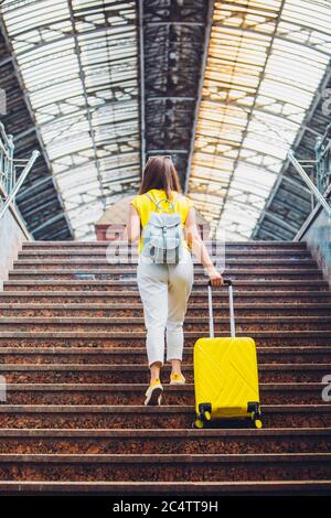 Frau mit gelber Tasche, die am Bahnhof über eine Treppe hinaufgeht Stockfoto