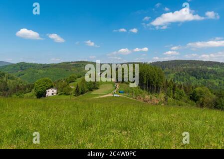 Wunderschöne Slezske Beskydy Berge in der Nähe von Filipka Hügel in Tschechien mit Wiese, wenigen isolierten Häusern, Feldwegen und Hügeln im Hintergrund durin Stockfoto