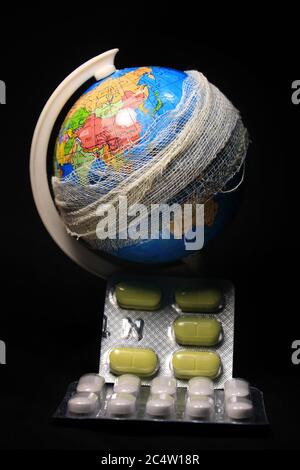 Der Globus und Pillen auf schwarzem Hintergrund. Metapher der globalen Pandemie des Corona-Virus. Stockfoto