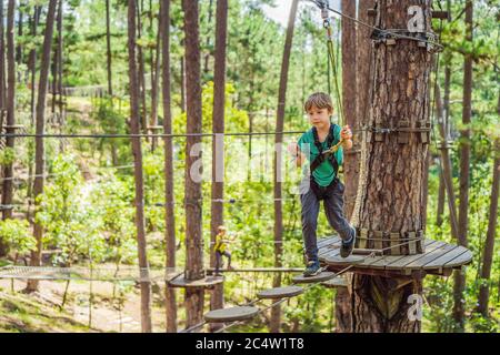 Portrait von niedlichen kleinen Jungen Spaziergang auf einer Seilbrücke in einem Abenteuer Seilpark Stockfoto