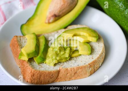 Avocado in Scheiben geschnitten und Avocado Toast auf weißem Teller Hintergrund Früchte gesunde Ernährung Konzept / Avocado Dip püriert Stockfoto