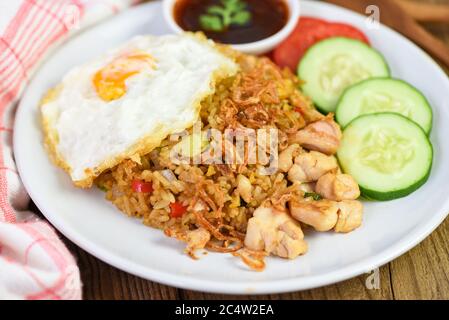 Nasi Goreng gebratenes Reis-Huhn mit Ei Tomate Gurke auf weißem Teller und Sauce / Nasi Goreng Ayam indonesische Küche Asiatisch Stockfoto