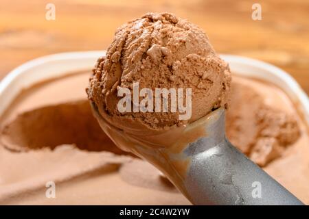Seitenansicht Löffel aus der Nähe nehmen eine Eiscreme Kugel aus der Schachtel mit Schokoladengeschmack Eis Stockfoto