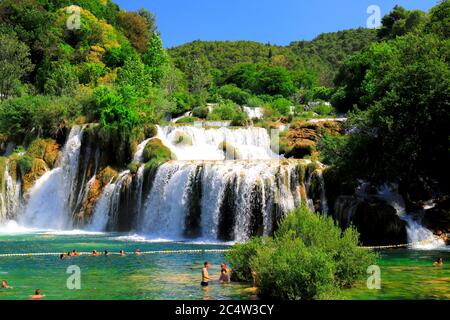 Touristen schwimmen im Sommer in der Nähe des malerischen Wasserfall. Die großen schönen kroatischen Wasserfälle, Flüsse, Berge und Natur. Krka Stockfoto