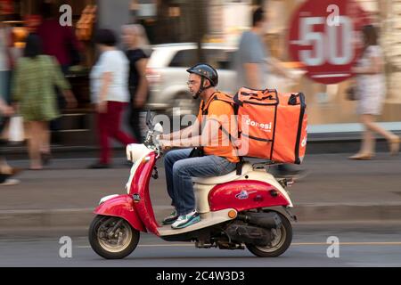 Belgrad, Serbien - 25. Juni 2020 : Lieferdienst Kurier Reiten einer zweifarbigen rot beige vintage vespa Roller im Stadtverkehr, schwenken Stockfoto