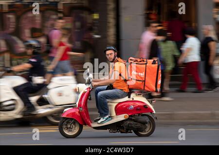 Belgrad, Serbien - 25. Juni 2020 : Lieferdienst Kurier Reiten einer zweifarbigen rot beige vintage vespa Roller im Stadtverkehr, schwenken Stockfoto