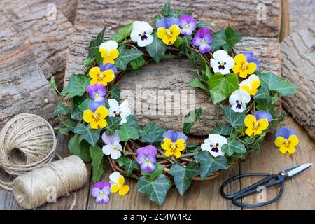 Rustikaler Kranz aus Viola-Blüten in lila und gelb Stockfoto