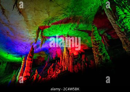 Beleuchtet mit den bunten Lichtern Stalaktiten und Stalagmiten in atemberaubenden Innenraum der schönen Huanglong Yellow Dragon Cave auch Th Stockfoto