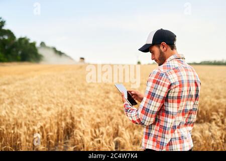 Smart Farming mit modernen Technologien in der Landwirtschaft. Mann Agronom Landwirt hält digitale Tablet-Computer in einem Weizenfeld stehen und mit Apps Stockfoto