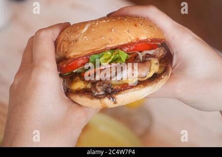 Selektive Aufnahme einer Person, die einen leckeren Hamburger hält Stockfoto