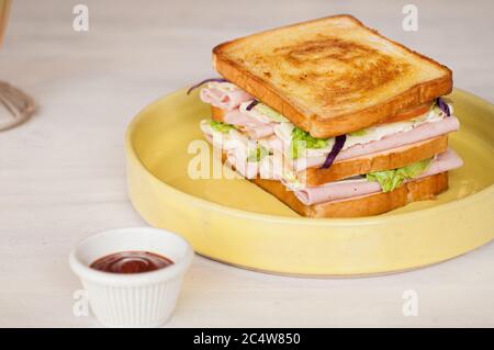 Selektive Fokusaufnahme eines Schinkensandwiches in einem gelben Platte Stockfoto