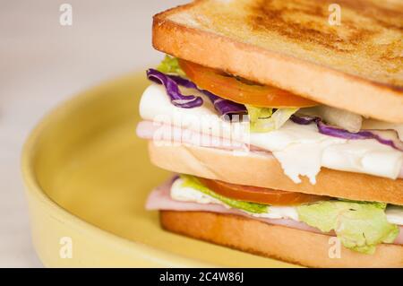 Selektive Fokusaufnahme eines Schinkensandwiches in einem gelben Platte Stockfoto