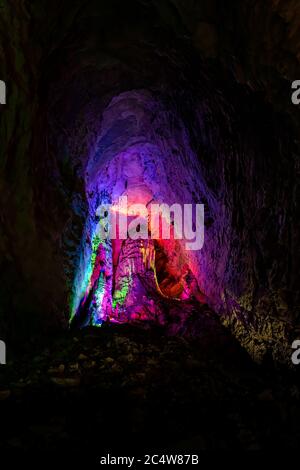 Beleuchtet mit den bunten Lichtern Stalaktiten und Stalagmiten in atemberaubenden Innenraum der schönen Huanglong Yellow Dragon Cave auch Th Stockfoto