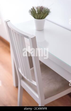 Weißer moderner Stuhl und ein Tisch mit einer Pflanze In einem Topf oben Stockfoto