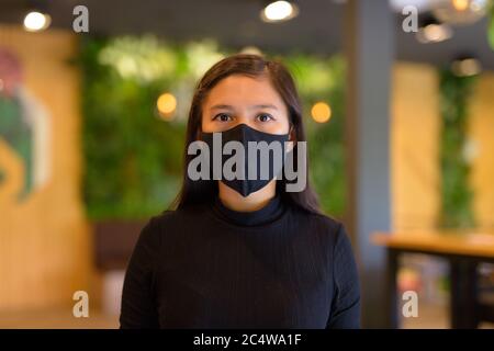 Gesicht der jungen asiatischen Geschäftsfrau trägt Maske und soziale Distanzierung im Café Stockfoto