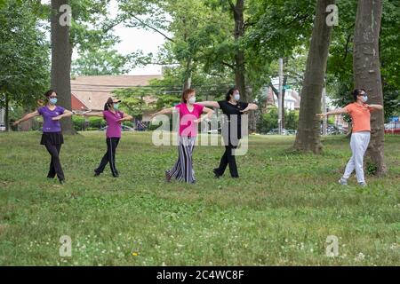 Maskierte asiatisch-amerikanische Frauen, wahrscheinlich chinesische Einwanderer, machen Tai Chi Übungen im Kissena Park in Flushing, Queens, New York City. Stockfoto