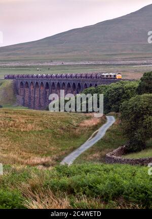 Bei Sonnenuntergang überquert ein Güterzug, der von zwei Lokomotiven der Klasse 66 gezogen wird, das Ribblehead Viadukt auf der Settle-Carlisle-Eisenbahnlinie, North Yorkshire. Stockfoto