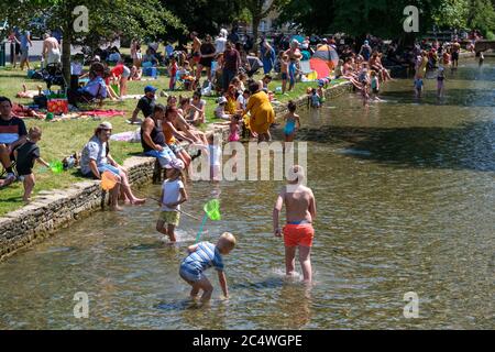 Bourton on the Water, Großbritannien. Die Menschen genießen die Sonne, paddeln im Fluss Windrush und entspannen im Schatten, da das anhaltend gute Wetter die Menschen nach draußen bringt mit der Lockerung der Sperrungen aufgrund von Covid-19 im Jahr 2020. Stockfoto