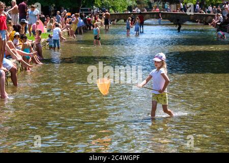 Bourton on the Water, Großbritannien. Die Menschen genießen die Sonne, paddeln im Fluss Windrush und entspannen im Schatten, da das anhaltend gute Wetter die Menschen nach draußen bringt mit der Lockerung der Sperrungen aufgrund von Covid-19 im Jahr 2020. Stockfoto