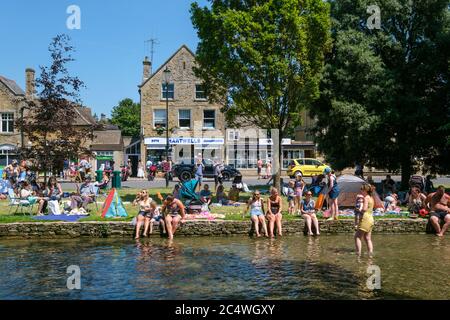 Bourton on the Water, Großbritannien. Die Menschen genießen die Sonne, paddeln im Fluss Windrush und entspannen im Schatten, da das anhaltend gute Wetter die Menschen nach draußen bringt mit der Lockerung der Sperrungen aufgrund von Covid-19 im Jahr 2020. Stockfoto