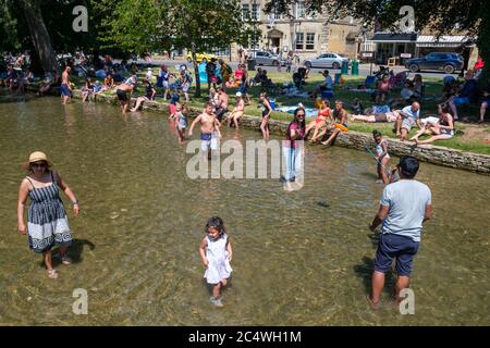 Bourton on the Water, Großbritannien. Die Menschen genießen die Sonne, paddeln im Fluss Windrush und entspannen im Schatten, da das anhaltend gute Wetter die Menschen nach draußen bringt mit der Lockerung der Sperrungen aufgrund von Covid-19 im Jahr 2020. Stockfoto