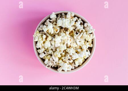 Popcorn in einer pinken Schüssel auf pinkem Hintergrund, Draufsicht Nahaufnahme Stockfoto