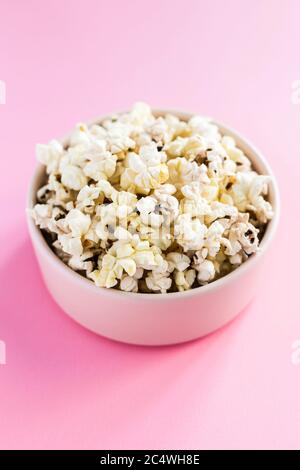 Popcorn in einer pinken Schüssel auf pinkem Hintergrund Nahaufnahme mit 45 Grad Winkel Stockfoto