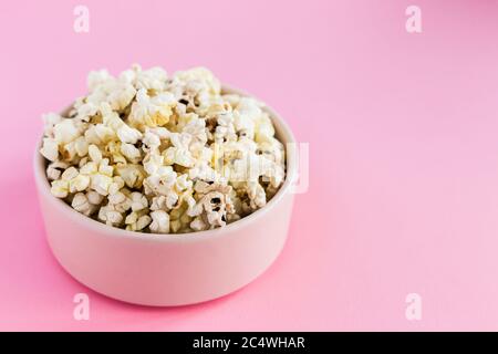 Popcorn in einer pinken Schüssel auf rosa Hintergrund Nahaufnahme Stockfoto