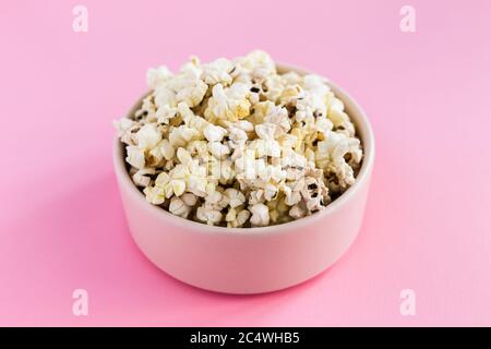 Popcorn in einer pinken Schüssel auf pinkem Hintergrund Stockfoto